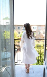 Una donna con un vestito bianco che guarda fuori da una finestra di Nota Bene Hotel & Restaurant a Lviv
