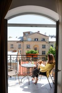 uma mulher sentada numa cadeira com uma criança numa varanda em Nota Bene Hotel & Restaurant em Lviv
