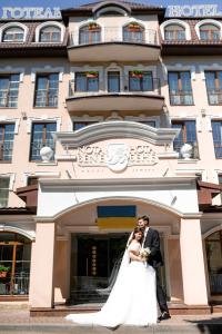 eine Braut und ein Bräutigam stehen vor einem Hotel in der Unterkunft Nota Bene Hotel & Restaurant in Lwiw