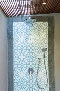 a bathroom with a shower with a blue and white wall at Suga Estate - Rice Field View Villas in Ubud