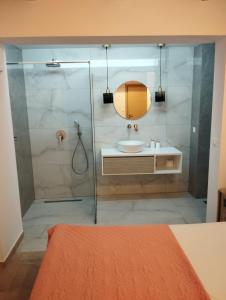 a bathroom with a shower with a sink and a mirror at Green Oasis House in Filerimos in Ialysos