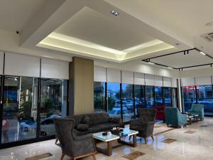 a living room with couches and chairs and windows at Banoj Hotel in Erbil