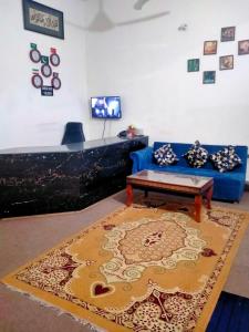a living room with a blue couch and a rug at Peridot Cottage in Islamabad