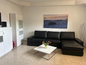 uma sala de estar com um sofá de couro preto e uma mesa em Haus Meeresbrise em Grömitz