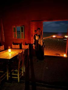 a woman standing in front of a table in a restaurant at Auberge Sahara Iriki & Désert Tours in Foum Zguid