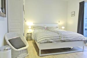 a white bedroom with a bed and a chair at Druvebeam in Oudega
