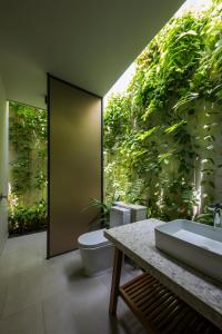 bagno con 2 servizi igienici e parete di piante di Villa Wyndham Phu Quoc a Phu Quoc