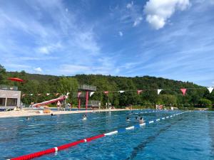 a large swimming pool with people in the water at Modernes Apartment in alter Burg nahe Fulda in Schlitz
