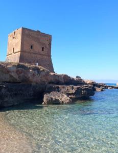 a building on a cliff next to the water at LA TERRAZZA SUL MARE camera fronte mare&vicino aereoporto SICILIAN VINTAGE STYLE SEASIDE ROOM in Cinisi