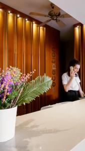 a woman talking on a phone in front of a table with flowers at Hawaii Hotel in Marmaris +91 photos