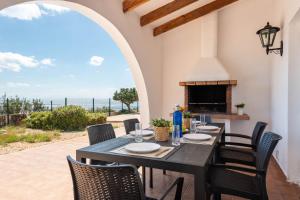 a dining room with a table and chairs and a fireplace at Villa Panorama in Cala'n Porter