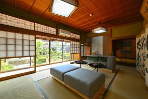 Pokój z łóżkiem, kanapą i oknami w obiekcie Hideaway Tabaki w mieście Echizen