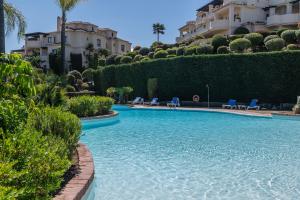 a swimming pool in front of a building at 2-bed apartment in Capanes del Golf in Benahavís