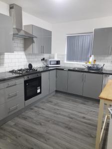 una cocina con electrodomésticos de acero inoxidable y armarios blancos en Double Bedroom with private bathroom and shared kitchen en Oldbury