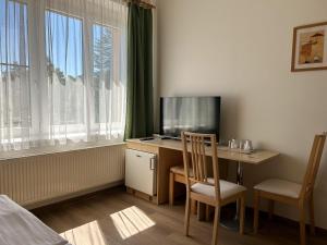 a room with a desk with a tv and a computer at Pension Fontana in Poděbrady