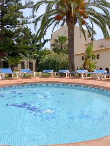 - une piscine avec des chaises bleues et un palmier dans l'établissement Great Duplex Apartment in Marbesa, à Marbella