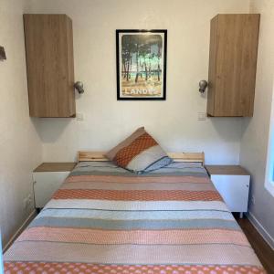 ein Bett in einem Schlafzimmer mit einem Bild an der Wand in der Unterkunft Au milieu des pins, charmant appartement de 38 m2 - 4 personnes - Domaine du Golf in Lacanau-Océan