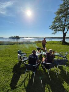 a group of people sitting at a table by the water at Valjevikens camping in Sölvesborg