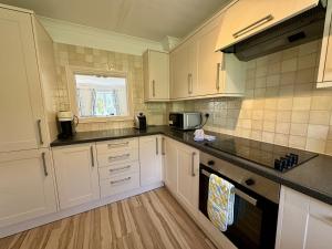 una cucina con mobili bianchi e una finestra di Primrose Cottage - South facing cottage in the heart of Dittisham a Dittisham Altre 22 foto