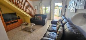 een woonkamer met een leren bank en een tv bij Casa San José in Nerja