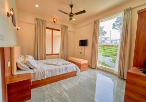 a bedroom with a bed and a large window at Glen Castle Vagamon Pool Resort by VOYE HOMES in Vagamon