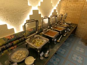 Hotel Mumbai House, Malad في مومباي: بوفيه مع العديد من صواني الطعام على منضدة