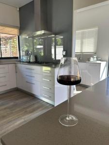 a glass of wine sitting on a counter in a kitchen at Luxury holiday home 3 bedroom, 3 bathroom house in Nahoon in East London