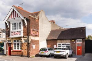 GloucestershireにあるQueens Head Apartmentsのレンガ造りの建物の前に停められた車両2台
