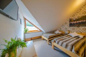 a attic room with two beds and a window at Olza Karczma i pokoje in Istebna