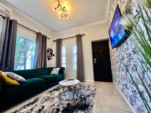 ein Wohnzimmer mit einem grünen Sofa und einem Flachbild-TV in der Unterkunft 435 on vale boutique aparthotel in Johannesburg
