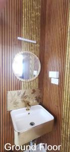 a bathroom with a sink and a light on a wooden wall at Olive Hills Yelagiri - Families Only - Full Duplex House - Yelagiri in Yelagiri