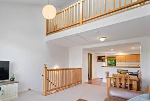 a living room with a staircase and a kitchen at Aspen Getaway in Queenstown