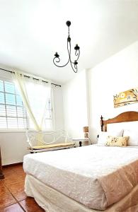 a white bedroom with a large bed and a chandelier at La Casita Nueva in El Socorro