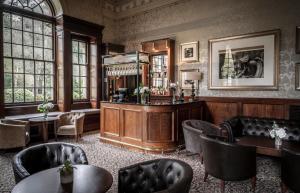 a bar in a room with chairs and tables at Crathorne Hall in Yarm