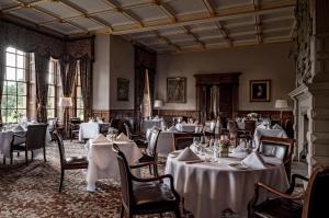 a dining room with white tables and chairs at Crathorne Hall in Yarm