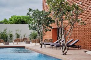 a pool with chairs and trees next to a brick wall at Villa Wyndham Phu Quoc in Phu Quoc