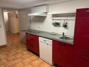 a kitchen with red cabinets and a sink at Haus Roseneck-Pension Am Stadtrand in Borchen
