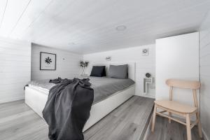 a white bedroom with a bed and a chair at Waterfront Cabins in Gothenburg