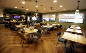 Travelodge Madrid Metropolitano في مدريد: مطعم فيه طاولات وكراسي في الغرفة