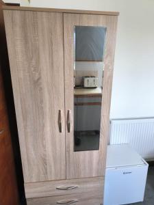 a cupboard with a mirror and a microwave in it at Guest House Bungalow in Walsall