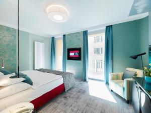ein Schlafzimmer mit einem Bett, einem Sofa und einem TV in der Unterkunft Hotel Capricorno in Wien