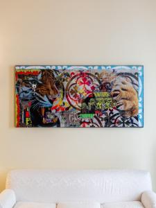 a painting on a wall above a white couch at Casa Misette 200mq a due passi dal mare in Alassio