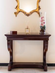 a table with a vase of flowers and a mirror at Casa Misette 200mq a due passi dal mare in Alassio