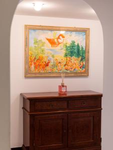 a painting on a wall above a wooden dresser at Casa Misette 200mq a due passi dal mare in Alassio
