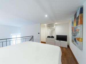 a white bedroom with a bed and a tv at Casa Misette 200mq a due passi dal mare in Alassio