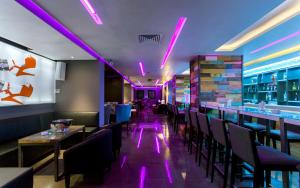 un ristorante con illuminazione viola, tavoli e sedie di Business Hotel a Tunisi