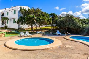a swimming pool with two chairs and a house at Biniforcat in Cala en Forcat