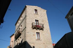a tall brick building with a balcony and flowers on it at Guest House Le Gemelle in Luras