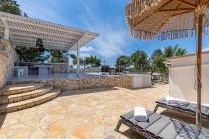 an outdoor patio with chairs and an umbrella at Antipaxos sunset house in Antipaxos