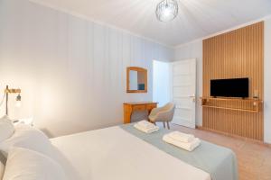 a white bedroom with a bed and a television at Antipaxos sunset house in Antipaxos